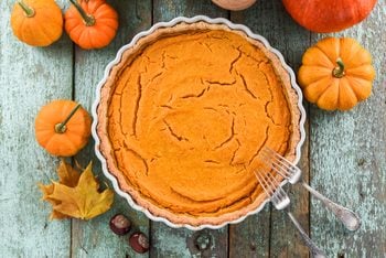 cracked pumpkin pie with pumpkins and leaves to the side
